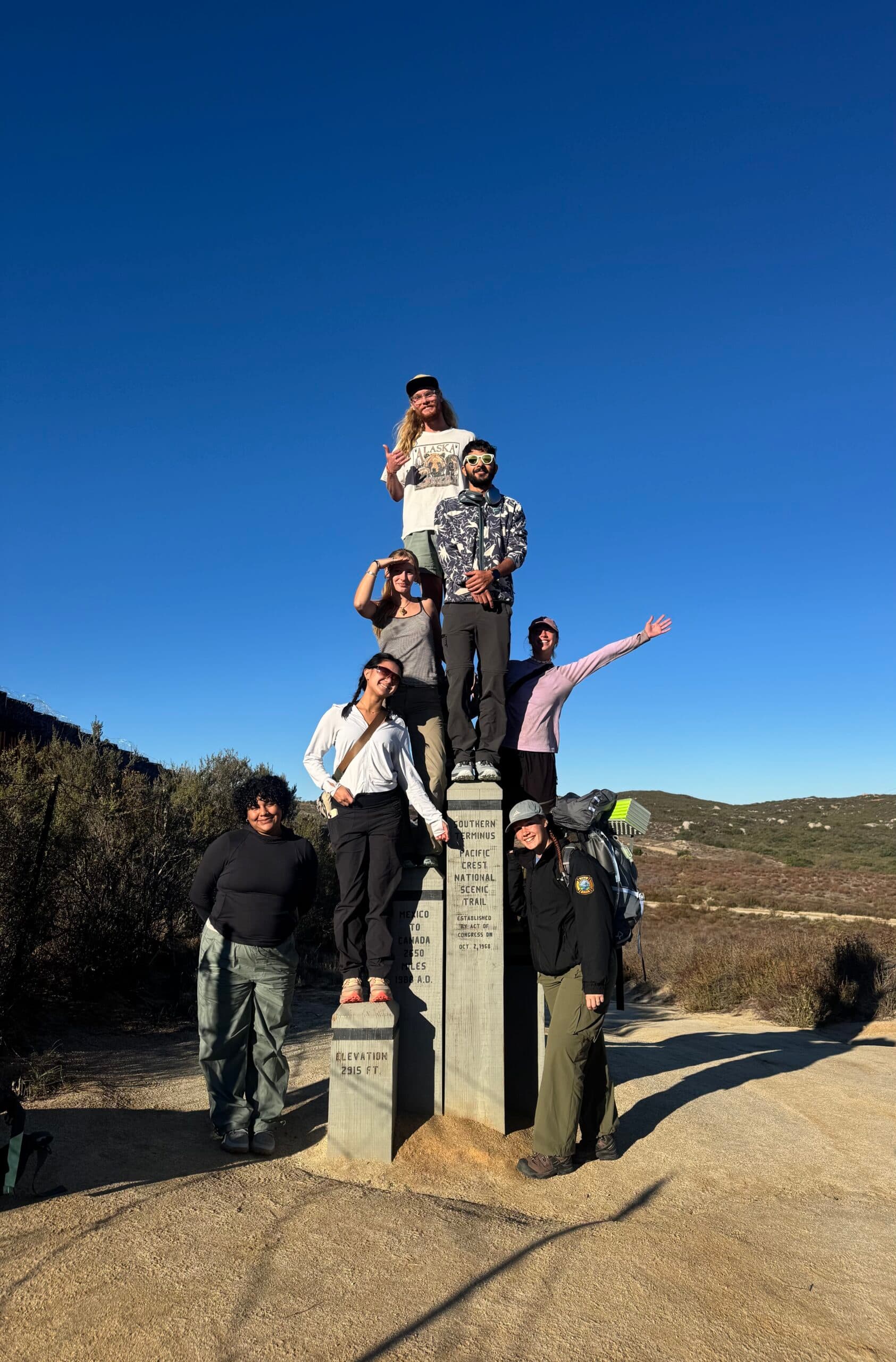 Group of hikers at the Pacific Crest Trail Southern Terminus monument on the California border